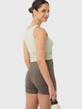 Top deportivo color verde pistacho, con breteles anchos, corte crop, espalda deportiva y abertura en el hombro.