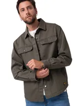 Chaqueta tipo sobrecamisa de sarga color verde oliva, con cierre frontal de botones, bolsillos en el pecho con solapa y bolsillos laterales. Presenta un forro interior de franela cepillada y etiqueta de marca en el bajo.