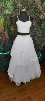 Conjunto blanco de top corto bordado con breteles finos y falda de tul con volados, puntilla, apliques de piedras y perlas.