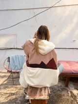 Campera con capucha de calce amplio, diseño en bloques de color beige, rosado y marrón, con aplique textil en la espalda que simula un paisaje montañoso. Cuenta con cierre delantero y bolsillos.