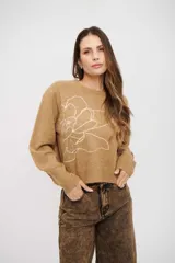 Sweater de tejido de punto color tostado, con cuello redondo, mangas largas con puños acanalados y diseño holgado. Presenta un delicado bordado lineal de una flor en el frente.