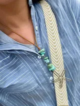 Collar con dije de estrella de mar y piedras turquesas irregulares, engarzadas en hilo de cuero marrón.