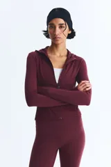 Campera deportiva de corte ajustado con capucha, cierre frontal completo y bolsillos laterales con cierre. Confeccionada en tejido funcional con tecnología de absorción de sudor, presenta mangas largas con aberturas para los pulgares.