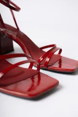 Sandalias de tacón cuadrado medio, color negro con acabado brillante, diseño de tiras finas en el empeine y cierre de pulsera con hebilla al tobillo.