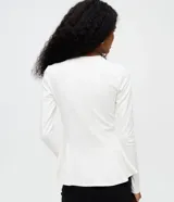 Blusa peplum de manga larga en punto roma color blanco, con cuello redondo y diseño estructurado de corte amplio en el ruedo.