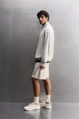 Sudadera gris claro de algodón con interior de rizo, cuello alto con cremallera, manga larga, bolsillos laterales y logo estampado en el pecho.