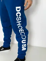 Pantalón de jogging azul con cordón ajustable en la cintura y gran estampado vertical de la marca en la pierna izquierda.