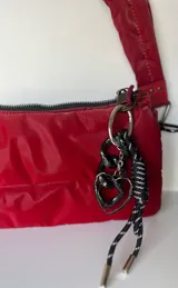 Llavero negro con cordón de nylon trenzado en blanco y negro, con dije de corazón metálico negro y eslabones de resina negra.