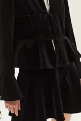 Falda corta de terciopelo negro con diseño ajustado en la cadera y volado en el ruedo.