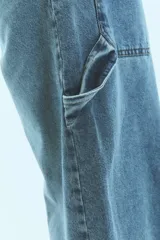 Jean de corte baggy y tiro bajo, en color azul lavado. Presenta un diseño holgado con presillas anchas y cierre frontal con botón metálico.