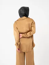 Camisa color ladrillo de corte amplio y mangas largas, con cuello camisero y cierre frontal con botones.