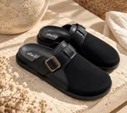 Zueco de diseño cerrado en el empeine, color negro, confeccionado con combinación de material textil y sintético, con tira ajustable y hebilla metálica dorada.
