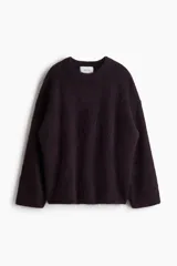 Buzo de punto oversized color morado oscuro, con textura suave y peluda, cuello redondo y hombros caídos.
