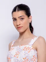 Top blanco con estampado floral en tonos naranja y lila, de corte cropped y breteles anchos.