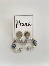 Aros colgantes con base de metal plateado y dije circular con perlas grises, blancas y transparentes.