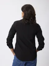 Camisa de manga larga en color negro, con cuello clásico y cierre frontal de botones. Presenta un corte entallado y puños con botones.