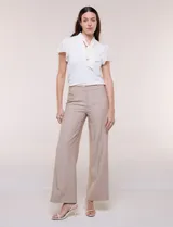 Pantalón sastrero de talle alto y corte wide leg, color beige, con pretina ancha, pasacintos, bolsillos laterales funcionales y bolsillos traseros ojalados.