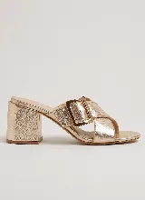 Sandalia de taco ancho color dorado, confeccionada en cuero vacuno, con diseño de tiras cruzadas y hebilla metálica decorativa.