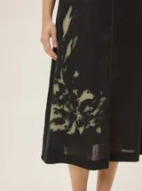 Vestido midi negro de lino con escote en V, sin mangas, de corte recto y holgado, con detalle de estampa abstracta en el lateral inferior.