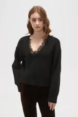 Sweater negro de punto con escote en V profundo y detalle de encaje en el borde del cuello. Presenta mangas largas con puños acanalados y un corte holgado.