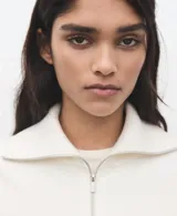 Jersey de punto de manga larga, con diseño bicolor en blanco y negro, cuello alto con cierre de cremallera corta.