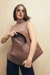 Cartera marrón de cuero sintético con forma irregular y tachas metálicas plateadas.