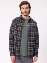 Camisa de manga larga con diseño a cuadros en tonos azul, verde y blanco. Presenta cuello clásico, cierre frontal con botones y un bolsillo en el pecho con el logo de la marca.