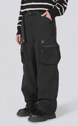 Pantalón cargo oversize de textil técnico color negro, con silueta relajada y múltiples bolsillos laterales de gran tamaño con cierres metálicos. Incluye cinturón integrado de cinta de seguridad con hebilla de encastre técnica.
