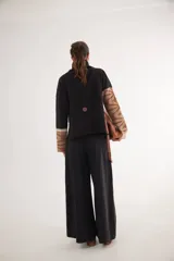 Pantalón de tiro alto en color azul, con cierre frontal de tres botones, pinzas en la cintura y corte holgado.