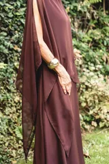 Vestido largo de gasa color bordó, con diseño de capas superpuestas y terminaciones en picos diagonales. Presenta mangas tipo capa que cubren sutilmente los brazos, brindando elegancia y libertad de movimiento.