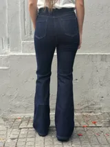 Jean de tiro alto en denim azul oscuro, con corte ajustado en la parte superior y levemente oxford en la botamanga. Presenta costuras verticales visibles a lo largo de la pierna que estilizan la silueta.