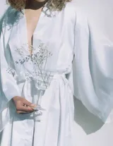 Kimono largo de seda blanca con mangas amplias y cinturón ajustable del mismo género.