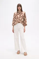 Camisa de corte holgado con estampado animal print tipo cebra en tonos negro y beige. Presenta cuello mao, cierre frontal con botones y un bolsillo aplicado en el pecho.