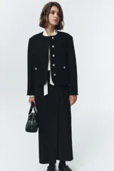 Chaqueta corta negra de lana con cuello redondo, botones metálicos plateados y bolsillos frontales con solapa.