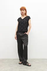 Blusa negra con bordado broderie de flores, escote en V y mangas cortas.