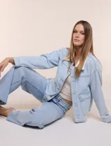 Campera de denim celeste claro con cuello y solapa en contraste de corderito blanco, de corte holgado, hombros caídos, cierre frontal con botones metálicos y bolsillos delanteros con solapa.