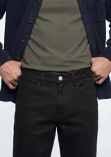 Pantalón de sarga de corte ajustado, color verde oscuro, con diseño clásico de cinco bolsillos y cierre frontal con botón y cremallera.