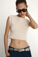 Top corto de punto color beige claro, con cuello redondo y mangas cortas tipo hombrera.