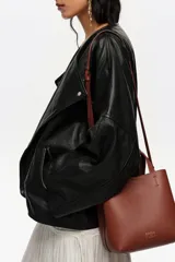 Bolso bandolera de tamaño pequeño de cuero marrón, con asas de mano, asa ajustable y logo grabado en dorado en el frente.