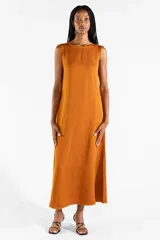 Vestido largo sin mangas de color mostaza, de corte recto y holgado, con escote redondo y bolsillos laterales. Confeccionado en mezcla de lyocell, viscosa y lino.