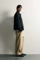Sobrecamisa negra de corte relaxed fit, confeccionada en tejido de algodón con elasticidad. Cuenta con cuello solapa, manga larga con puño abotonado, bolsillos de vivo en la cadera y cierre frontal de botonadura.