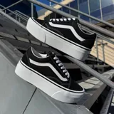 Zapatillas Vans Old Skool Stackform negras con la línea lateral blanca y suela de plataforma blanca.