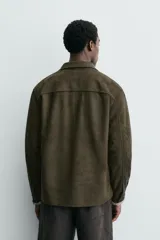 Sobrecamisa de corte regular confeccionada en tejido con efecto ante. Presenta cuello solapa, cierre frontal con botones, mangas largas con puños abotonados y un bolsillo de plastrón en el pecho.