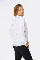 Blusa de manga larga blanca con estampado floral en negro, cuello redondo y cierre frontal con botones.