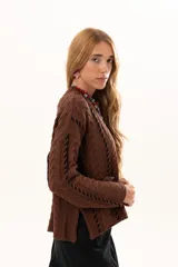 Buzo de tejido de punto color chocolate con diseño de trenzas verticales y detalles de costuras en contraste color negro. Presenta cuello redondo, mangas largas con terminación acampanada y aberturas laterales en el ruedo.