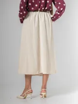 Falda midi de corte clásico confeccionada en corderoy, con cintura elastizada, diseño de tablas y bolsillos laterales. Incluye un cinturón desmontable en color marrón.