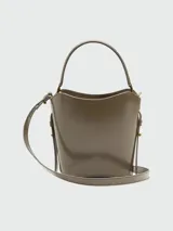 Minibolso tipo bucket de piel lacada color gris, con cierre de cordón ajustable y detalle de logo metálico dorado en forma de corazón con letra A. Cuenta con asa superior fija.