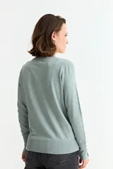 Sweater de punto liso color marrón topo, con cuello redondo y manga larga. Presenta un detalle de tres botones pequeños en la abertura del puño.