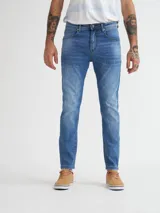 Pantalón de jean celeste de corte slim fit con efecto lavado y roturas sutiles.