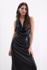 Vestido largo de fiesta color negro, confeccionado en crepe elástico con acabado brillante. Presenta un escote tipo cowl (caído) en el frente, diseño sin mangas y una silueta fluida y elegante.